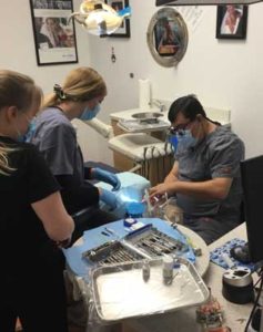 chairside dental assistant helps patient and dentist fix teeth